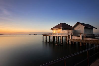 Building by sea against sky at sunset