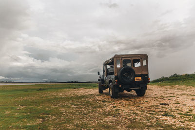 View of truck on field against cloudy sky