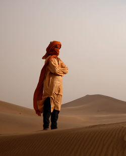 Full length of man on sand dune in desert against sky