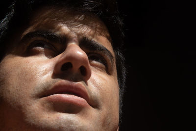 Close-up portrait of young man against black background