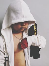 Close-up of boy standing against white background