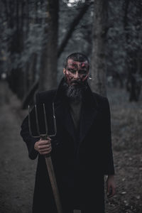 A man with a pitchfork as a demon in the forest