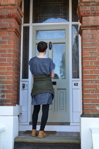 Rear view of man standing against door of building