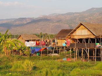 Houses on field by mountains against sky