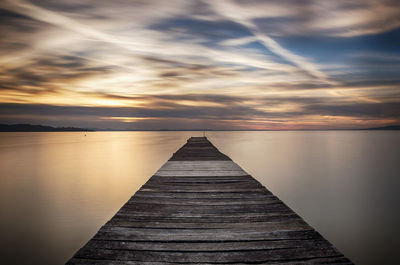 Pier over sea against sky during sunset