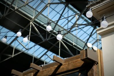 Low angle view of light bulbs hanging against roof
