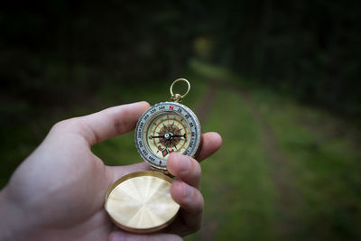 Cropped hand holding compass in forest