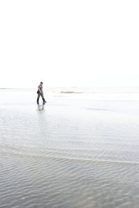 Man on beach against clear sky