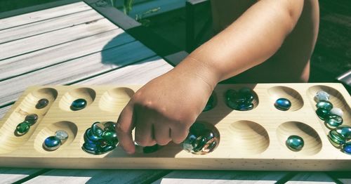 Midsection of boy collecting marbles on wooden palette