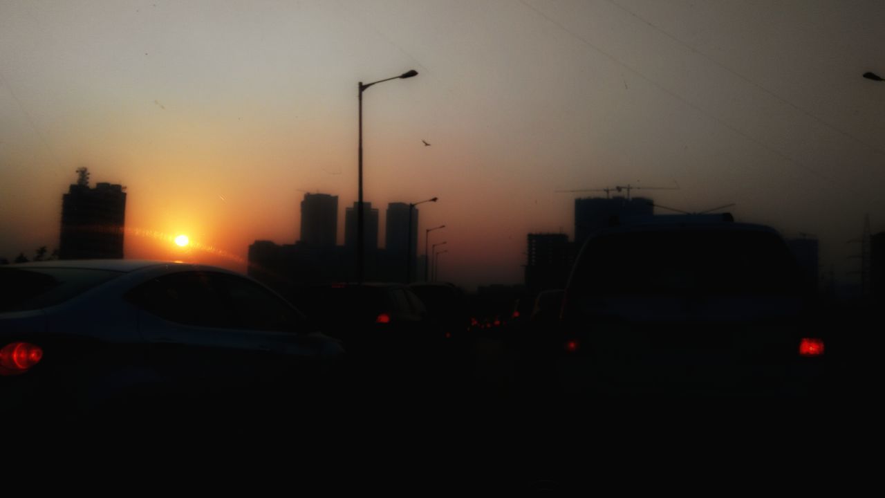 CARS ON ROAD AGAINST SKY AT SUNSET