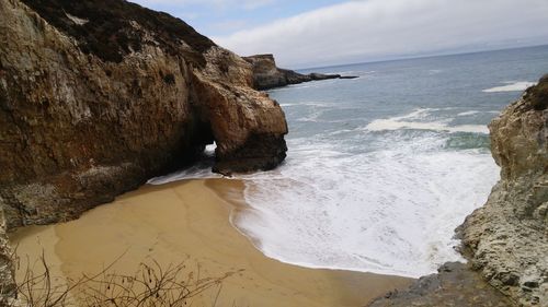 Scenic view of sea by cliff against sky