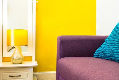 Close-up of sofa against yellow wall at home