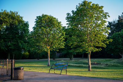 Empty bench in park against clear sky