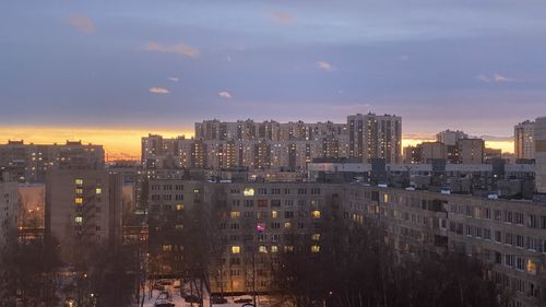 Illuminated buildings in city against sky during sunset
