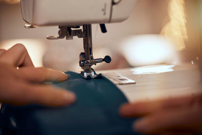 Cropped hand of person using sewing machine