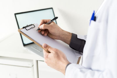 Male healthcare worker holding clipboard while writing on paper