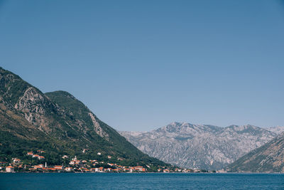 Scenic view of sea and mountains against clear blue sky