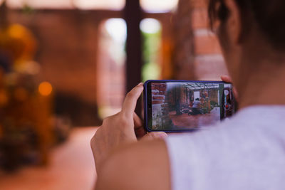 Rear view of woman photographing with mobile phone
