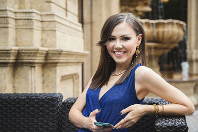 Portrait of young woman standing against wall