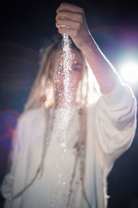 Young woman with dreadlocks spilling powder while standing outdoors at night