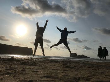 Silhouette people at beach against sky during sunset