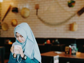 Young woman in hijab having coffee at cafe