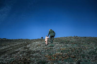 People on land against clear blue sky