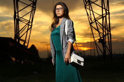 Portrait of young woman standing against sky during sunset