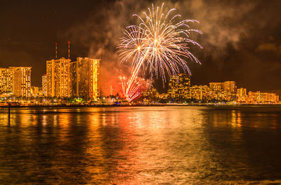 Hawaii friday firework display over river by buildings against sky at night