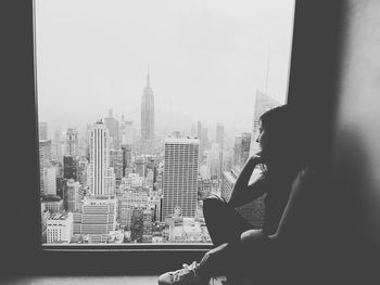 Silhouette of woman looking through window