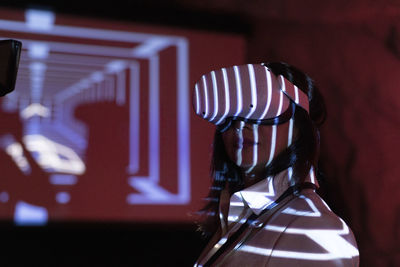 Mature businesswoman watching through futuristic glasses in illuminated workshop