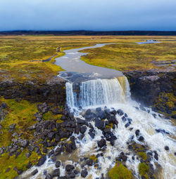 Scenic view of waterfall against sky