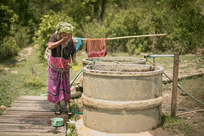 Mature woman washing face while standing outdoors