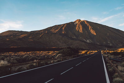 Road by mountain against sky