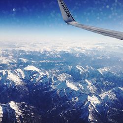 Cropped image of airplane flying over snowcapped mountains
