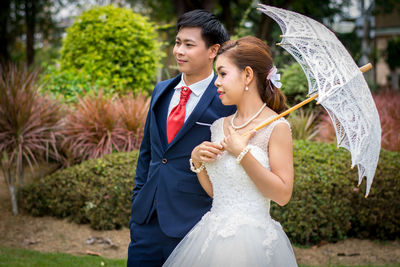 Bride and bridegroom standing at park