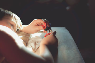 Close-up of boy playing with toy while lying on bed at home