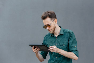 A young man in sunglasses holds a tablet in his hands and reads information on the tablet