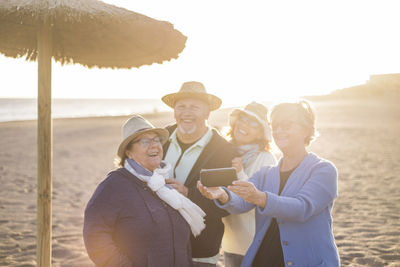 Happy people looking at smart phone on beach