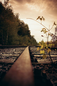 Surface level of railroad tracks against sky during sunset