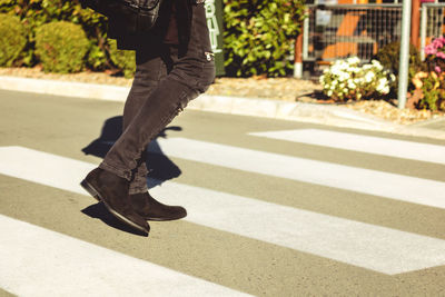 Low section of man crossing street