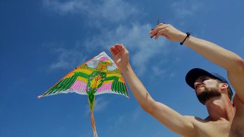 Low angle view of man holding kite against sky