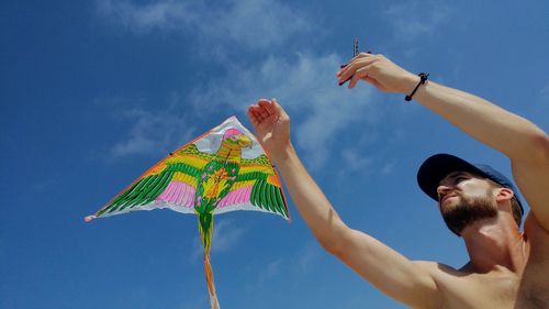 Low angle view of man holding umbrella against sky