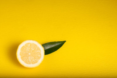 Close-up of orange slice over yellow background