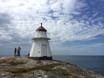 People on rock by sea against sky