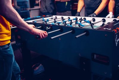 Midsection of people playing foosball on table