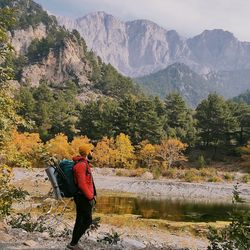 Rear view of man standing by lake against mountain