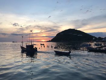 Boats moored on sea against sky during sunset