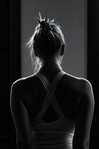 Rear view of woman standing against black background