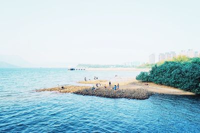 People on beach against clear sky